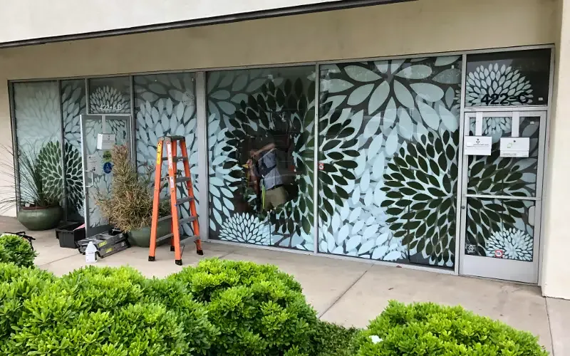 Storefront glass carrying a large-scale decorative privacy pattern.