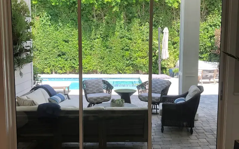 Finished sliding glass doors opening onto a pool patio, filmed for security and heat.