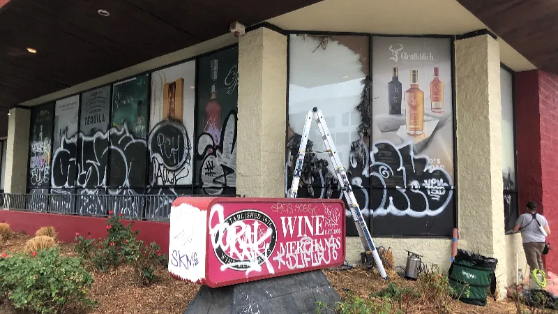 Storefront glazing covered in tagging, mid-way through a film replacement.